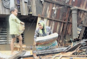 SITI KHADIJAH (kanan) mencari lebihan kayu-kayu sisa runtuhan rumahnya untuk digunakan membina penempatan sementara di Kampung Manik Urai Lama, Kuala Krai baru-baru ini. 